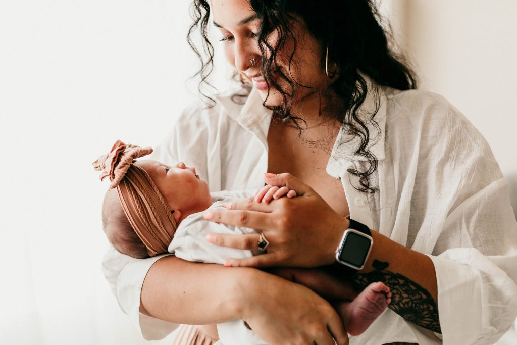 Mom holding newborn baby and smiling at eugene newborn photography studio