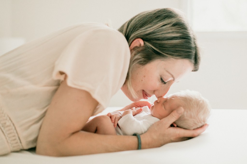 mom with her newborn baby girl giving her a kiss photographed by Heidi rakas for Eugene's best newborn photography studio