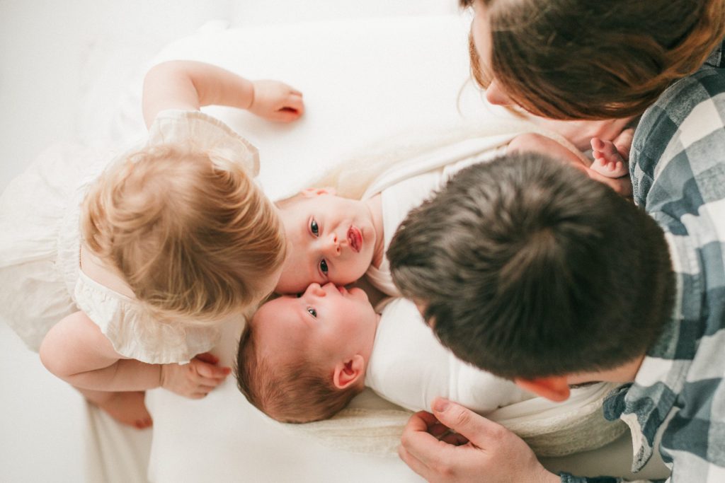 a toddler giving her newborn baby twin brothers a kiss during their photoshoot in eugene oreogn
