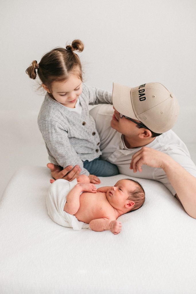 a dad with his newborn and older sibling during newborn photoshoot in Eugene Oregon