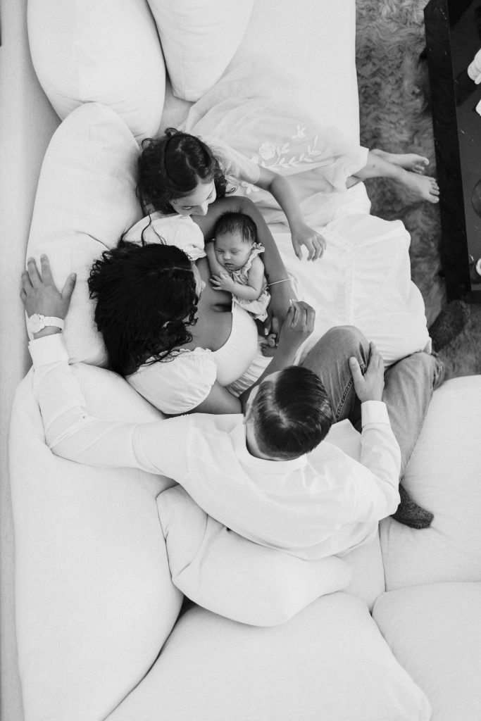 a family holding their newborn baby in a black and white image captured during their newborn photoshoot for Heidi Rakas Photography in eugene oregon