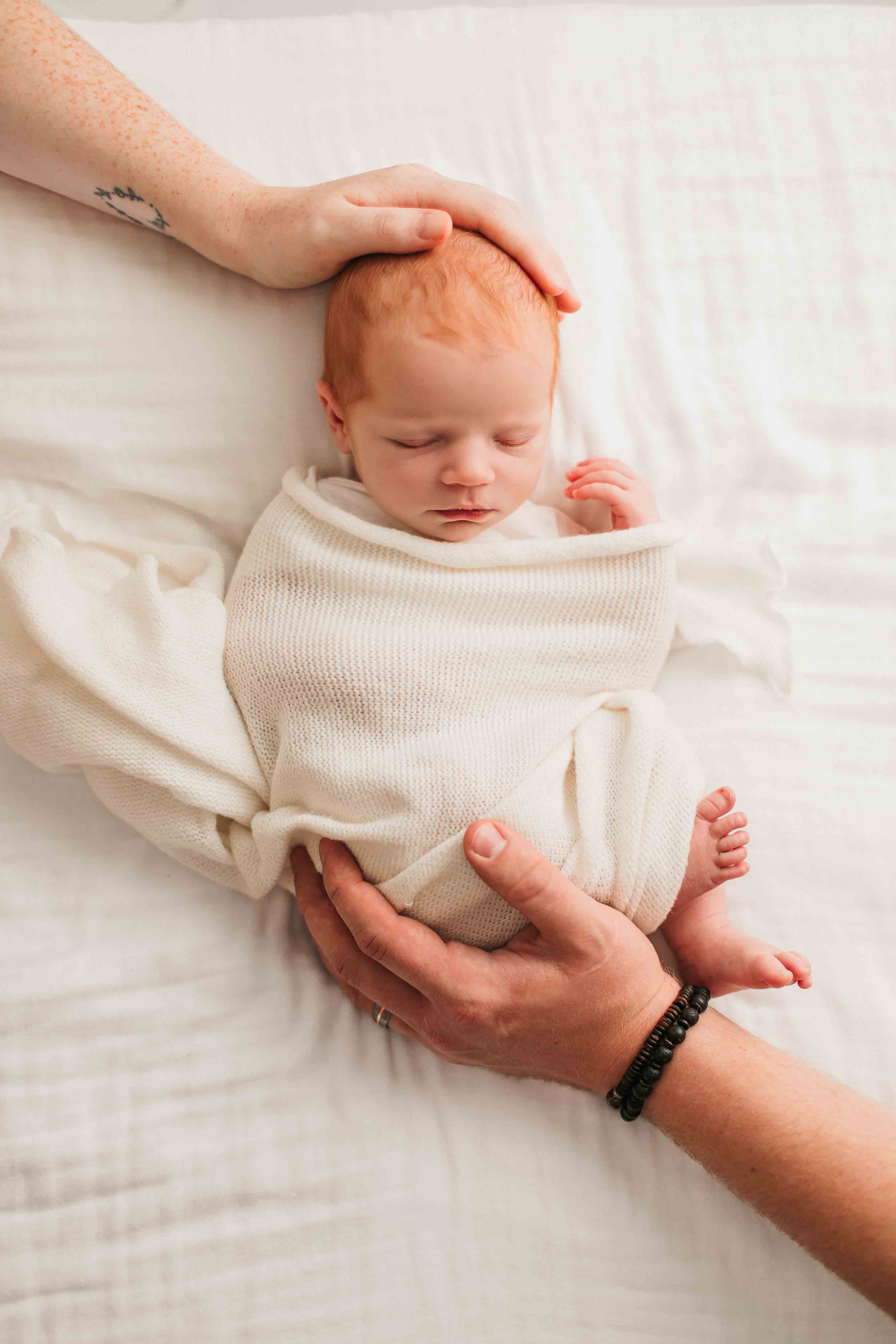 a newborn baby girl safe in her parents hands for Heidi Rakas Photography studio in Eugene Oregon